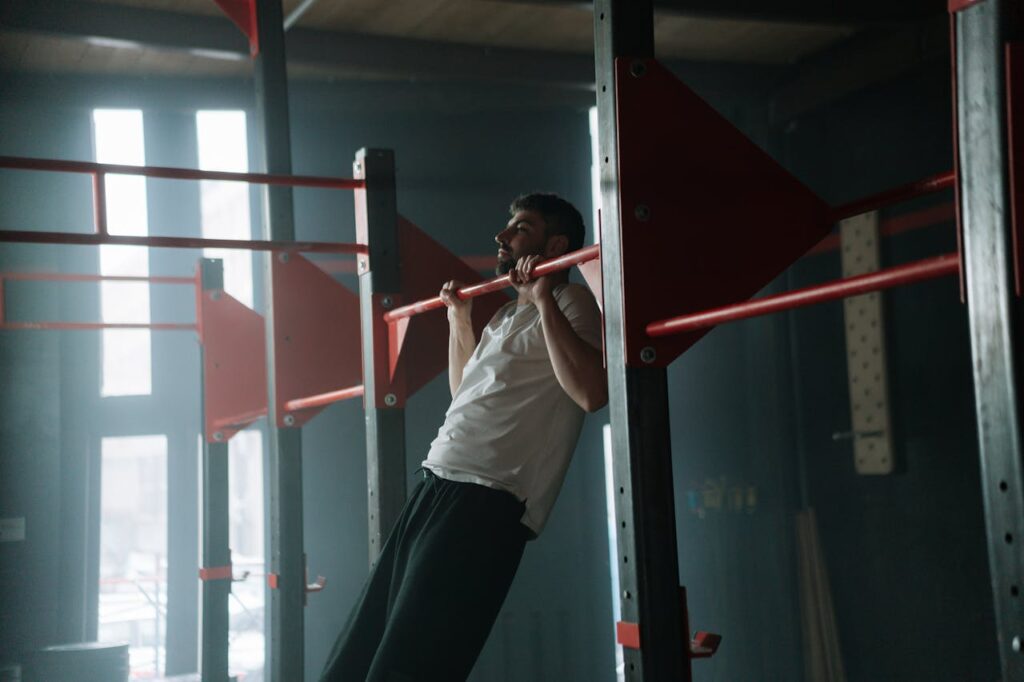 pexels-photo-9644816 Adult man doing pull-ups in a dimly lit indoor gym, focused on upper body training.